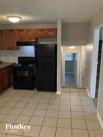 College Park house for rent - a kitchen with a black refrigerator and wooden cabinets
