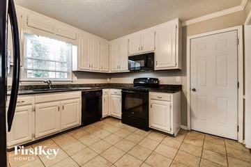 Marietta house for rent - A kitchen with white cabinets and black appliances.
