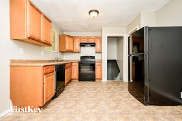 Ellenwood house for rent - A kitchen with wooden cabinets and a black refrigerator.