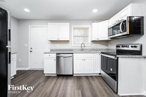 Decatur house for rent - a kitchen with white cabinets and stainless steel appliances