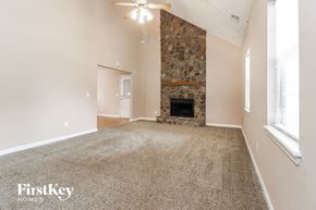 Gainesville house for rent - a carpeted living room with a fireplace and a ceiling fan