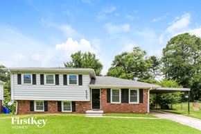 Riverdale house for rent - a white and brick house with a green lawn and a blue sky