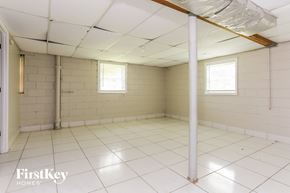 Riverdale house for rent - an empty room in a building with white tiled floors and walls and two windows
