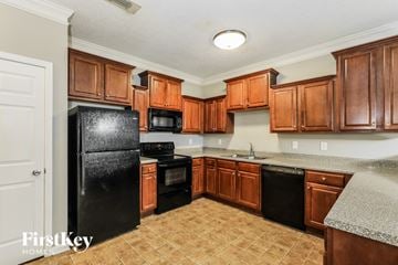 Atlanta house for rent - A kitchen with brown cabinets and black appliances.