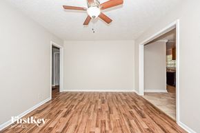 Forest Park house for rent - an empty living room with a ceiling fan and wood floors