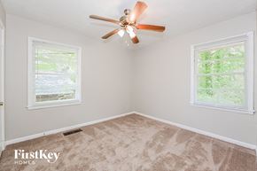 Forest Park house for rent - an empty bedroom with a ceiling fan and two windows