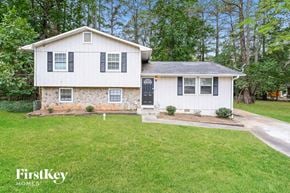 Lithonia house for rent - A white house with a black door and windows is surrounded by green grass.