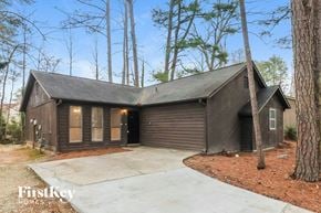Austell house for rent - A house with a garage is surrounded by trees.
