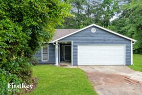 Riverdale house for rent - A blue house with a white garage door is surrounded by greenery.