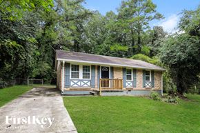 Jonesboro house for rent - A small house with a porch is surrounded by greenery.