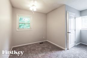 Jonesboro house for rent - A room with a carpeted floor, a window with a view of trees, and a door leading to another room.