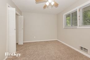 Riverdale house for rent - an empty bedroom with a ceiling fan and two windows