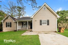 Jonesboro house for rent - A beige house with a porch and a garage door.