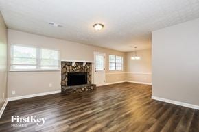 Jonesboro house for rent - A spacious room with a stone fireplace and wooden flooring.