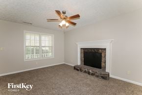 Jonesboro house for rent - a living room with a fireplace and a ceiling fan