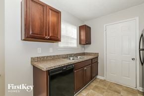 Jonesboro house for rent - a kitchen with brown cabinets and a sink and a refrigerator