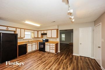 Peachtree City house for rent - A kitchen with wooden floors and a black refrigerator.