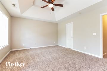 Mcdonough house for rent - the spacious living room has a ceiling fan and beige carpet
