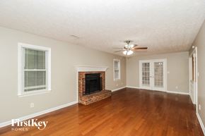 Peachtree City house for rent - an empty living room with a fireplace and a ceiling fan