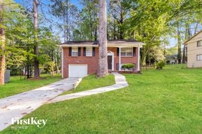 Jonesboro house for rent - A house with a garage is surrounded by trees.