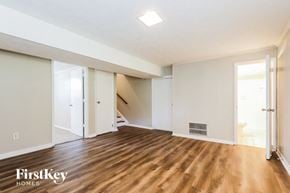 Jonesboro house for rent - A spacious room with wooden floors and white walls, with a staircase leading to another level.