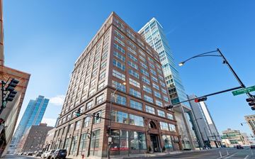 Chicago apartment for rent - A tall building with many windows is in the middle of a city street.