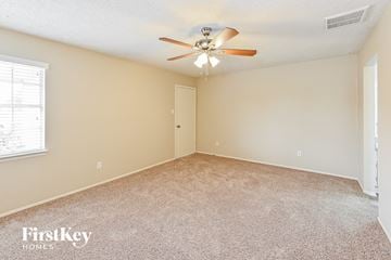 Deer Park house for rent - a spacious living room with carpet and a ceiling fan