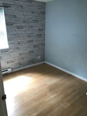 Vancouver apartment for rent - A room with a wooden floor and a stone wall.