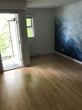Vancouver apartment for rent - A room with a wooden floor and a wall with a blue and white painting.