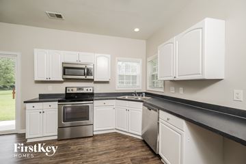 Moncks Corner house for rent - A kitchen with white cabinets and a black countertop.