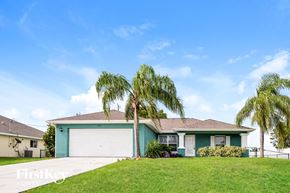 Cape Coral house for rent - A house with a blue garage door and a white fence.