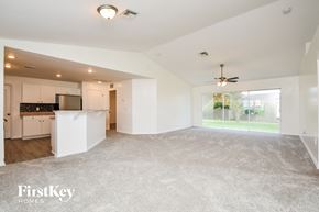 Cape Coral house for rent - A spacious living room with a kitchen area in the background and a carpeted floor.