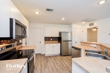 Cape Coral house for rent - A kitchen with a stove top oven, microwave, refrigerator, and sink.