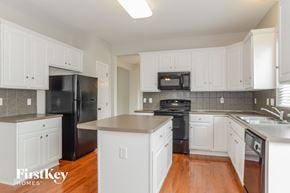 Kansas City house for rent - a renovated kitchen with white cabinets and black appliances