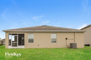 Port Orange house for rent - a small tan house with a grass yard and a blue sky