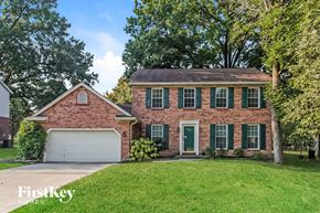 Mason house for rent - a brick house with green shutters and a white garage door