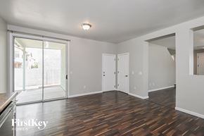 Tucson house for rent - A room with wooden floors and white walls, with a sliding glass door leading to a balcony.