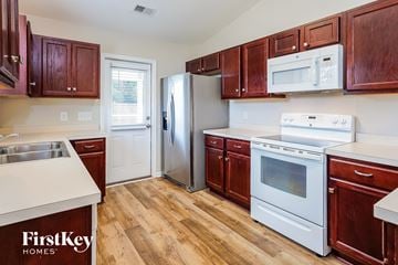 Summerville house for rent - a kitchen with wood flooring and white appliances and wooden cabinets