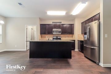 Dallas house for rent - A kitchen with dark brown cabinets and a black island.
