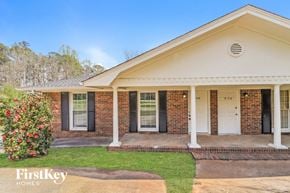 Powder Springs house for rent - A brick house with a porch and a bush in front.