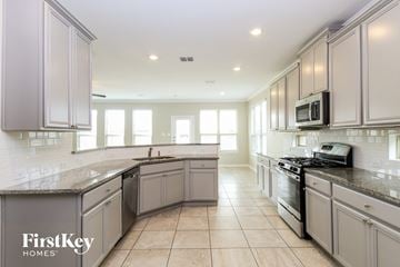 Haslet house for rent - a large kitchen with stainless steel appliances and white cabinets