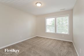 Mooresville house for rent - a bedroom with a carpeted floor and two windows