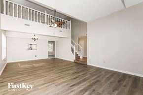 Indianapolis house for rent - A spacious room with wooden flooring and a staircase leading to another level.