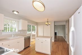 O'fallon house for rent - a kitchen with white cabinets and a long hallway with a sink and a counter top