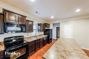 Calera house for rent - A kitchen with a black stove top oven and a black refrigerator.
