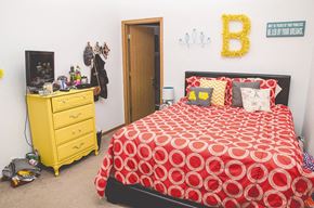 Ames apartment for rent - a bedroom with a red bed and a yellow dresser
