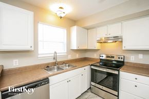 Noblesville house for rent - a kitchen with white cabinets and a sink and a stove