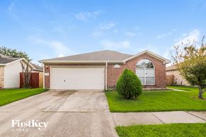 Baytown house for rent - A brick house with a garage door and a tree in front.