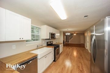 Ellenwood house for rent - a kitchen with white cabinets and stainless steel appliances and a wooden floor