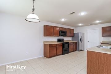 Fort Worth house for rent - a kitchen with wooden cabinets and a white tile floor
